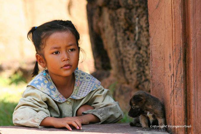 Kleines Mädchen und Welpe auf dem Gelände des Banteay Srei, Angkor, Kambodscha