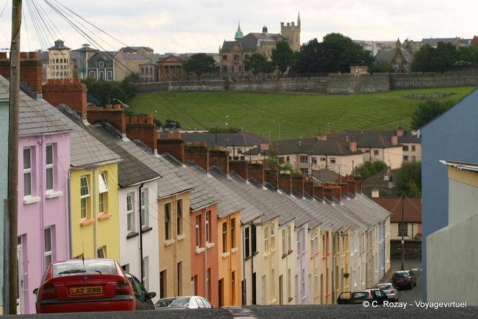 Steile Straße mit bunten Fassaden vor den Stadtmauern, Derry - Nord-Irland