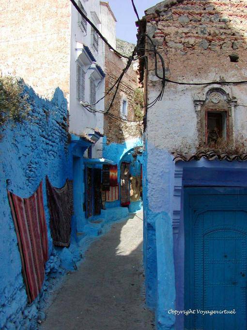 Teppiche hängen an der farbigen Wand, Chefchaouen - Marokko
