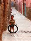 Ein Kind, das mit einem Reifen Gasse der Medina, Marrakesch, Marokko.