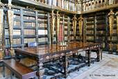 Arbeitstisch und Regalen der Bibliothek Joanine, Coimbra, Portugal.
