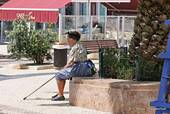 Praça Sousa Oliveira, sitzende Frau in traditioneller Tracht, Nazaré, Portugal.