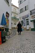 Die Frau in Schwarz in den Kopfsteinpflasterstraße, Nazaré, Portugal.