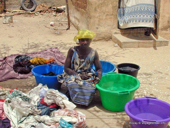 Frau hockt in der Mitte der bunten Wäscheeimer - Senegal