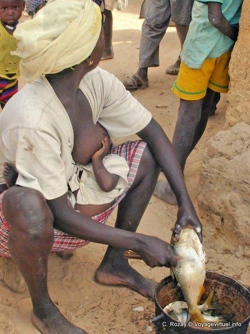 Frau füttert ihr Kind, während Abblättern Fische - Region Mbam - Senegal