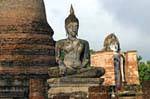 Buddha sitzt vor dem Phra Attharot, Sukhothai, Wat Mahathat, Thailand.